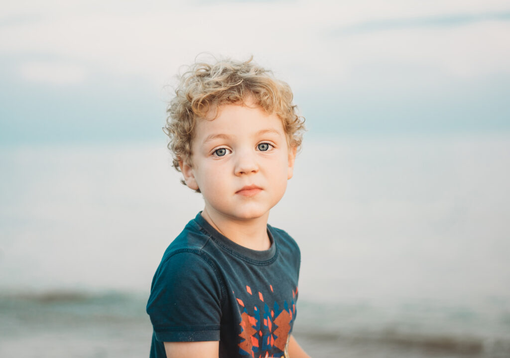 A boy looking at the camera on a family beach photoshoot in West Sussex