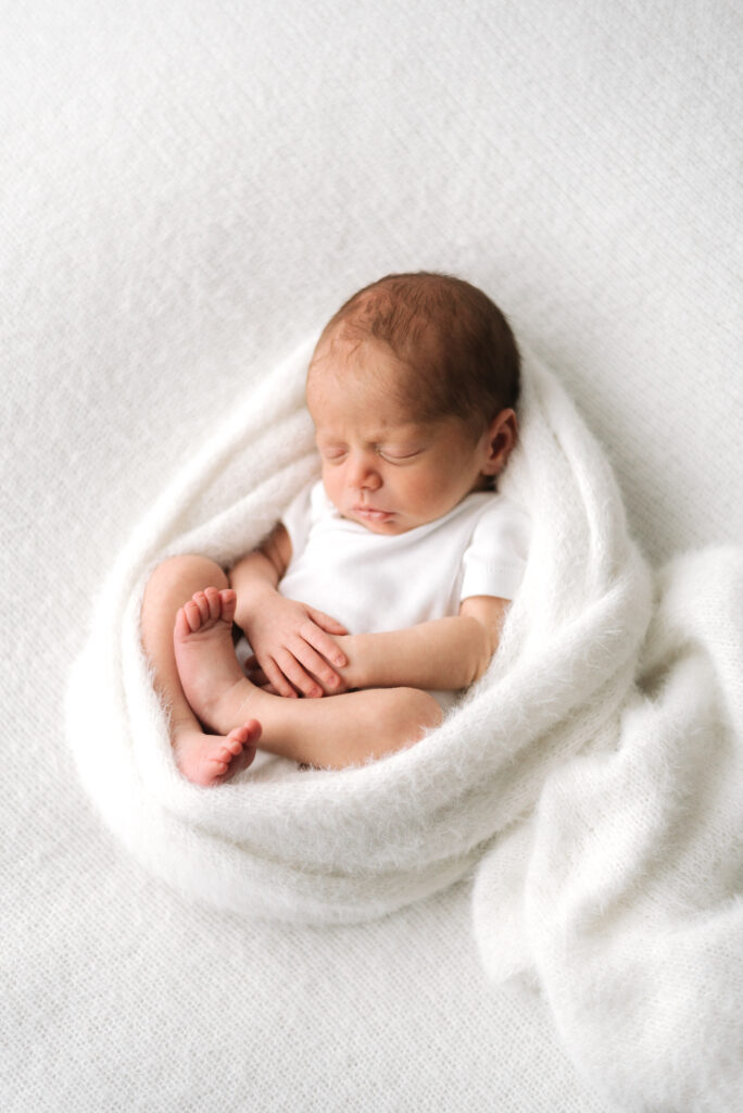 Newborn baby sleeping  in a white blanket at Horsham photoshoot