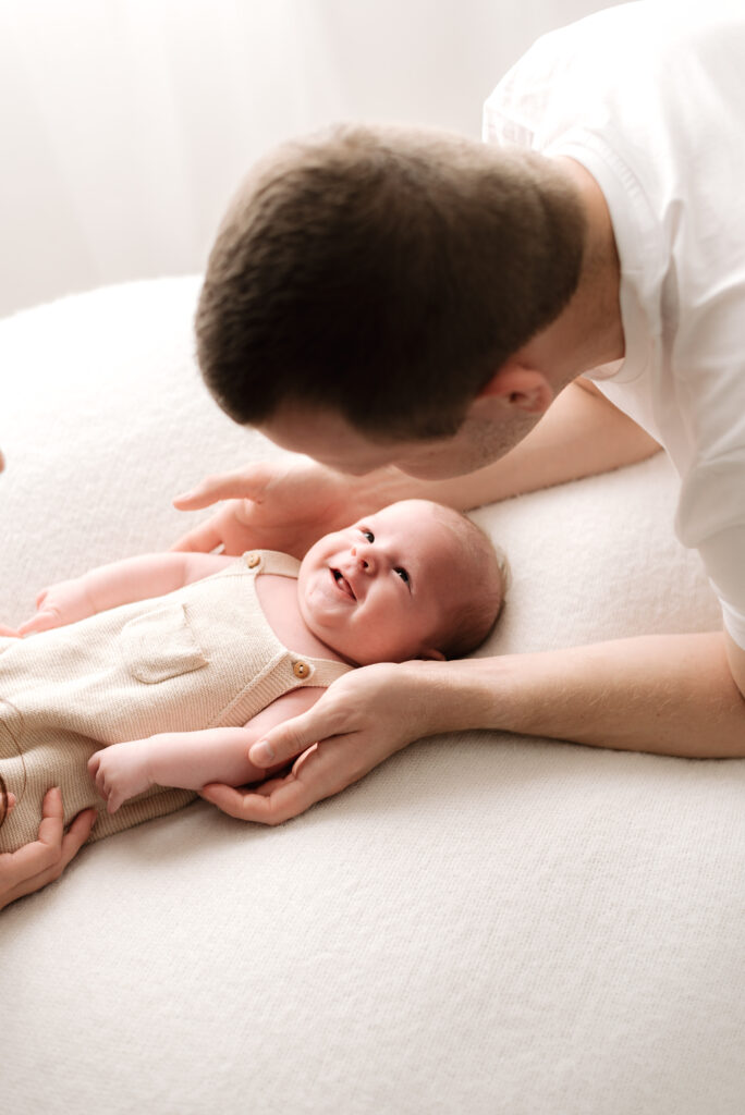 A dad leaning over his newborn baby at horsham newborn photoshoot