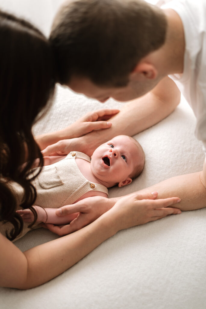 A mother and father leaning over their newborn baby at Horsham newborn photoshoot