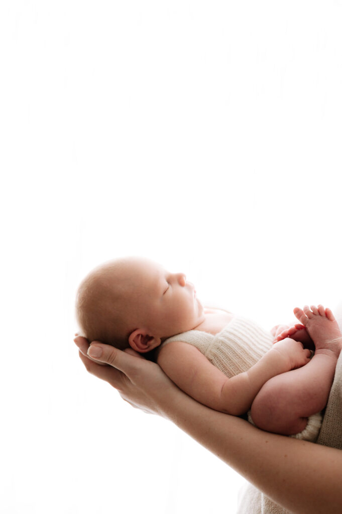 A baby sleeping in his mothers arms in a Horsham newborn photoshoot