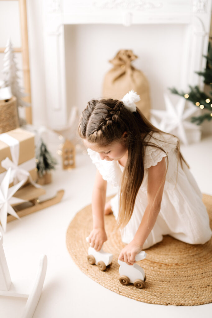 A girl playing with festive wooden toys at a natural christmas photoshoot in West Sussex