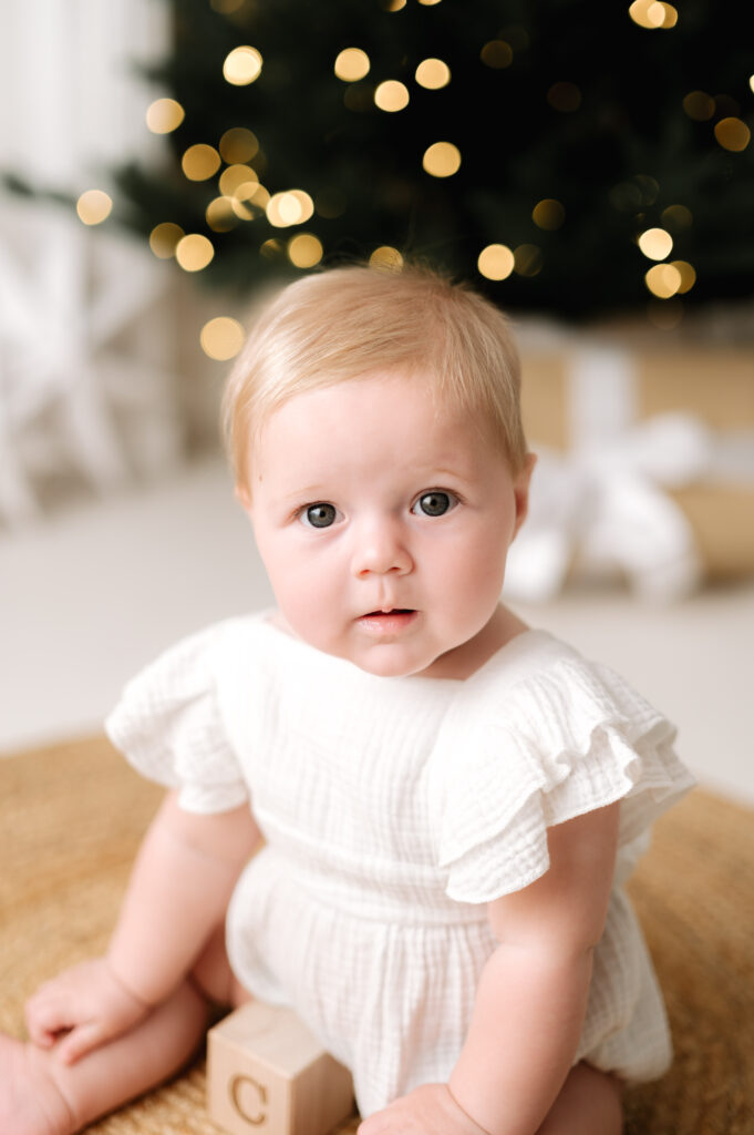 Baby girl sitting infront of natural christmas decor at a christmas mini session