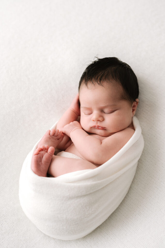 newborn baby girl wrapped up in a white soft blanket during a horsham newborn photoshoot