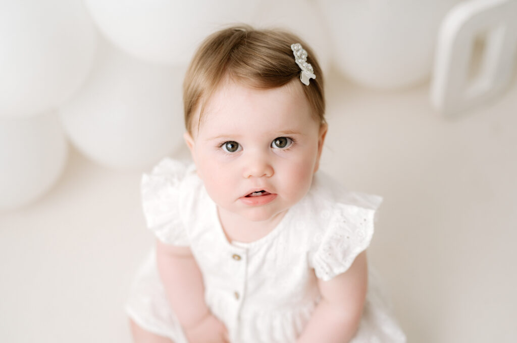 1 year old girl looking up at the camera whilst at a horsham photoshoot